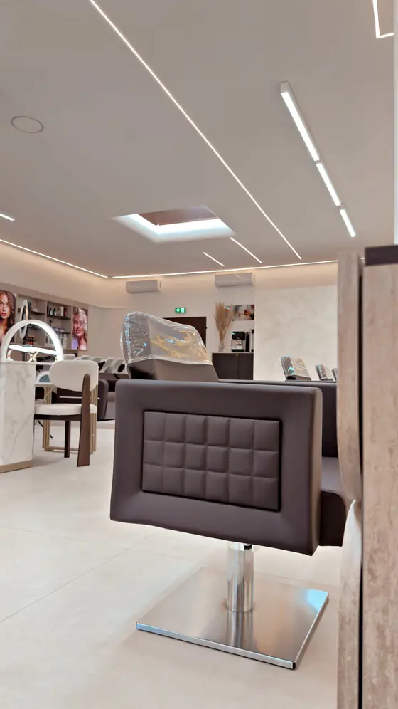Blick in den Salon mit Bedienstuhl, Lichtlinien an der Decke und Waschbereich