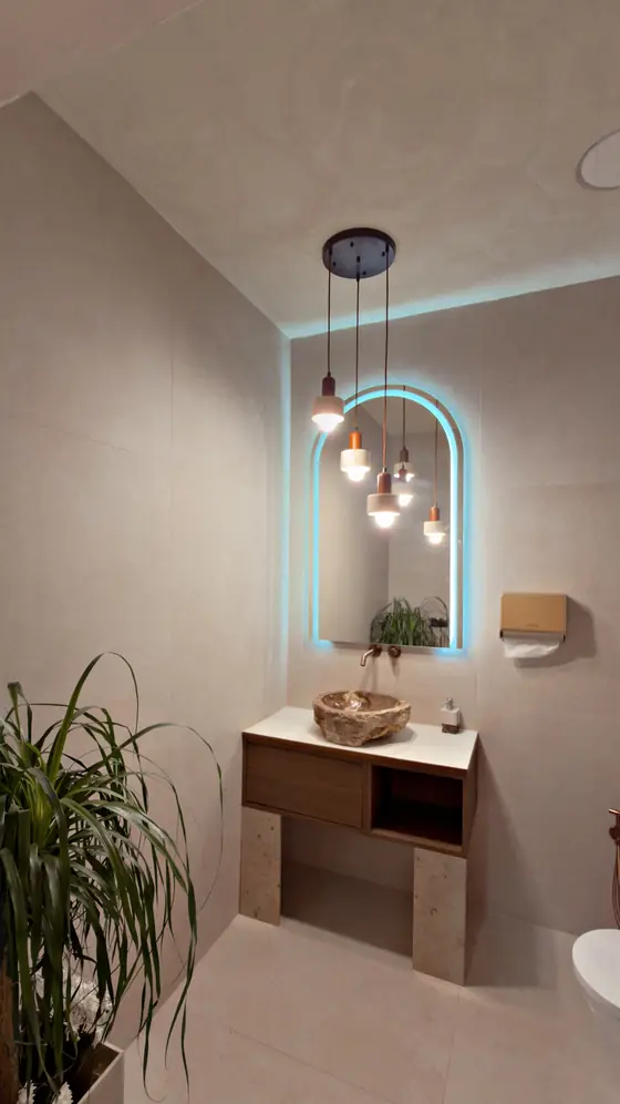 Gäste-WC mit Natursteinwaschbecken und beleuchtetem Bogenspiegel